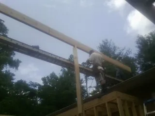 Carpenter setting a ridge beam over a new addition frame — Ice Dam Removal by Roofing Brothers in Arlee