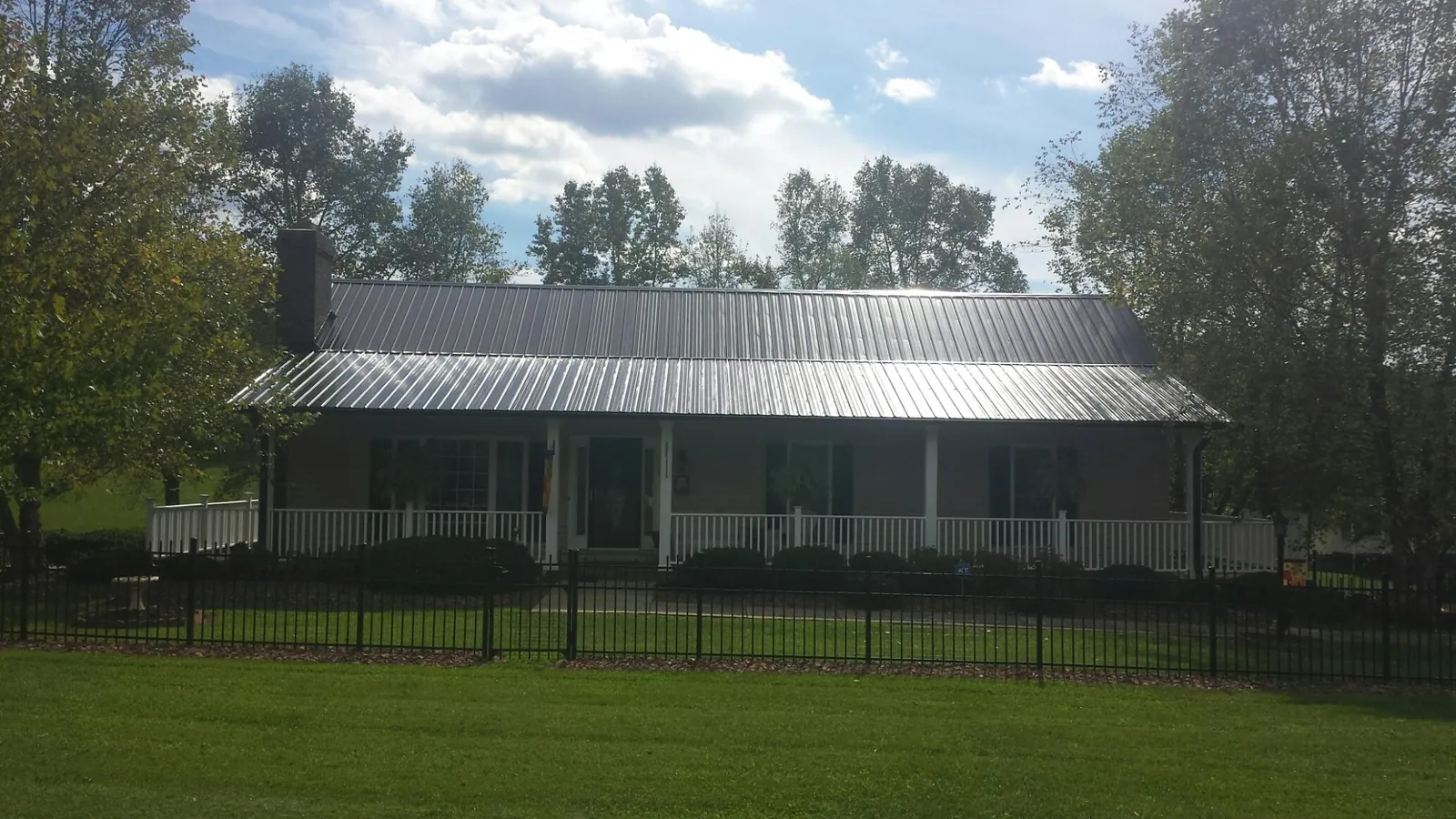 Gray metal roof on a brick ranch with a full width front porch — Gutter Guard Installation work by our crew in Arlee