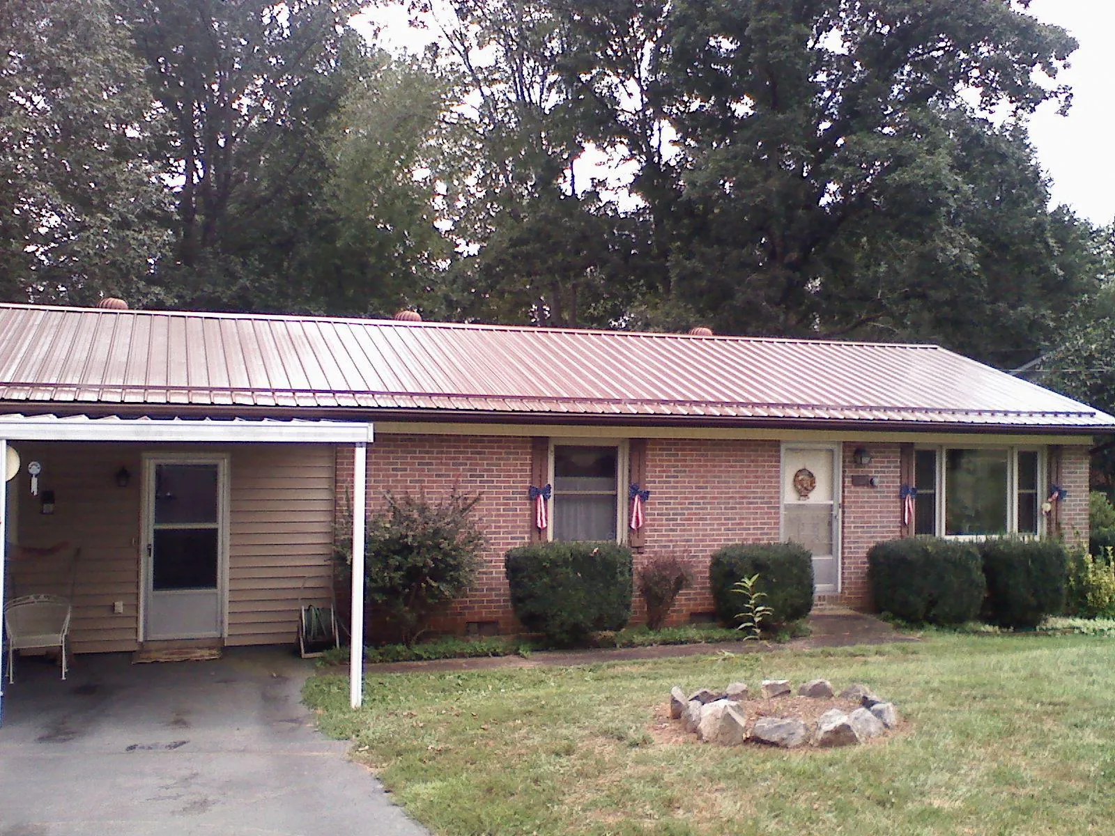 Bronze metal roof and carport on a brick ranch home — Roof Repair work by our crew in Arlee